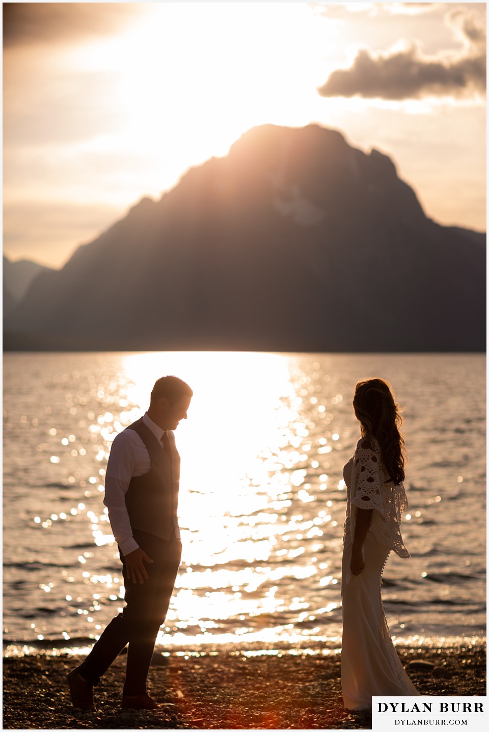 jackson lake lodge wedding grand tetons wyoming bride and groom walking in sunlight by the lake and mt moran