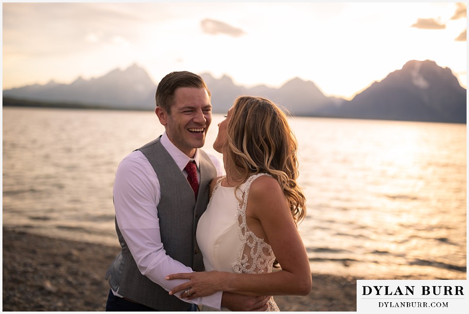 jackson lake lodge wedding grand tetons wyoming bride and groom laughing together near lake