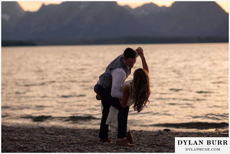 jackson lake lodge wedding grand tetons wyoming groom dipping bride while dancing near the lake