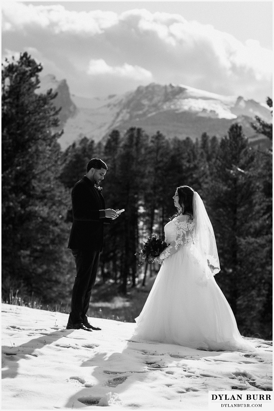 couple exchanging vows in snow with mountains in background in Colorado