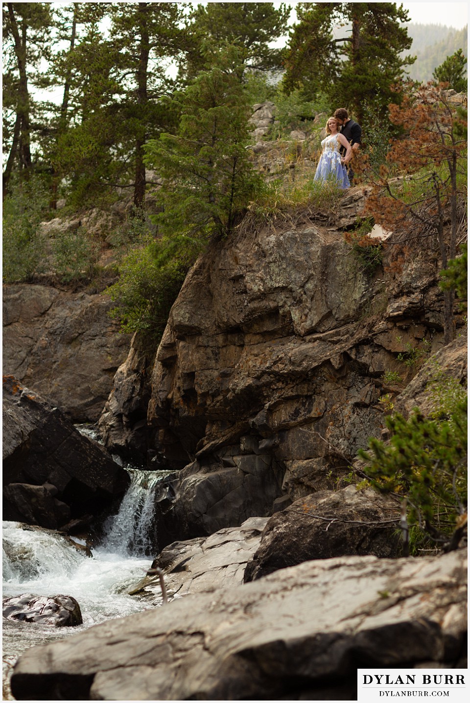 mmountain adventure elopement wedding colorado groom kissing brides cheek near cliff edge with river down below