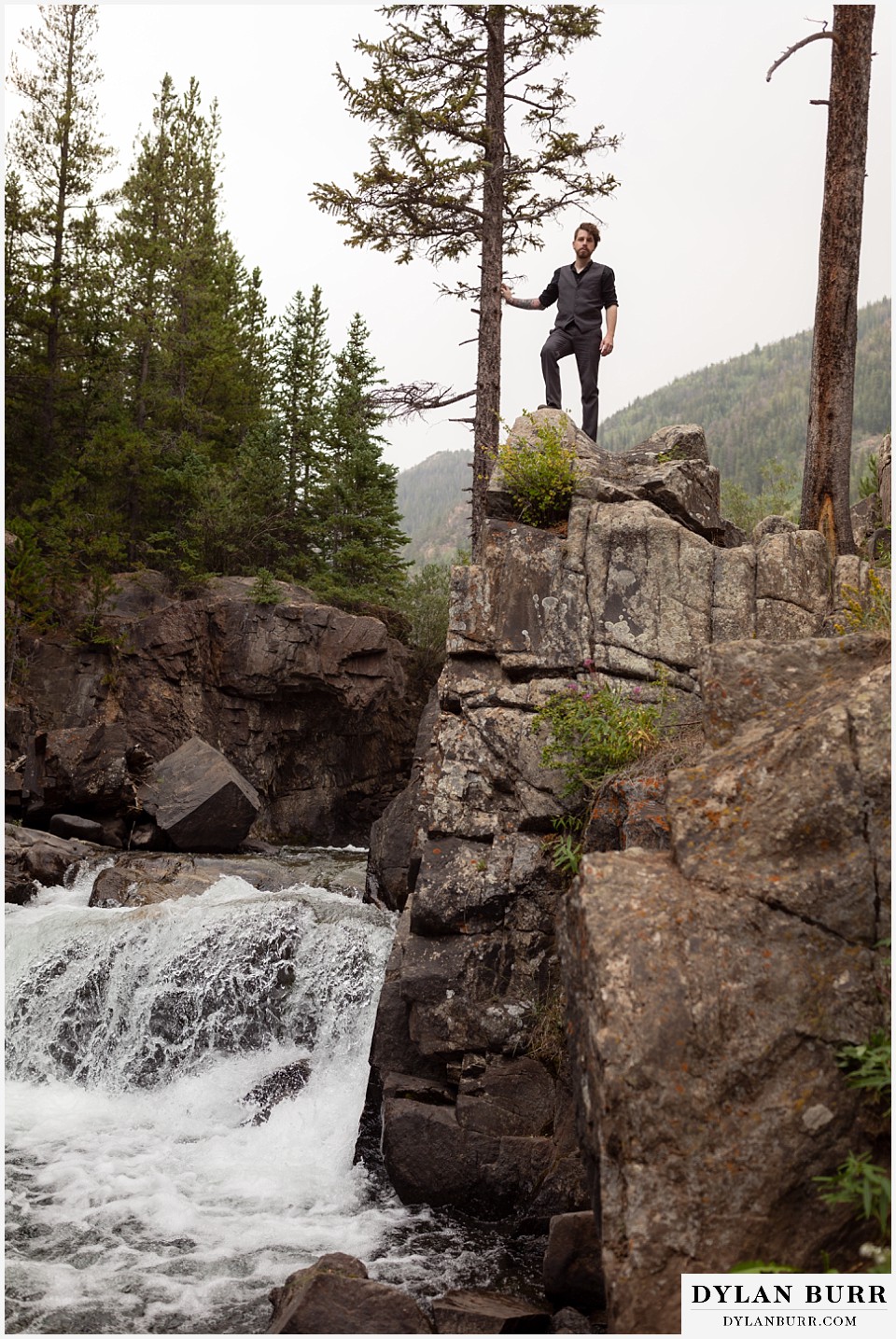 mountain adventure elopement wedding colorado groom standing all on mountain cliff with large waterfall below