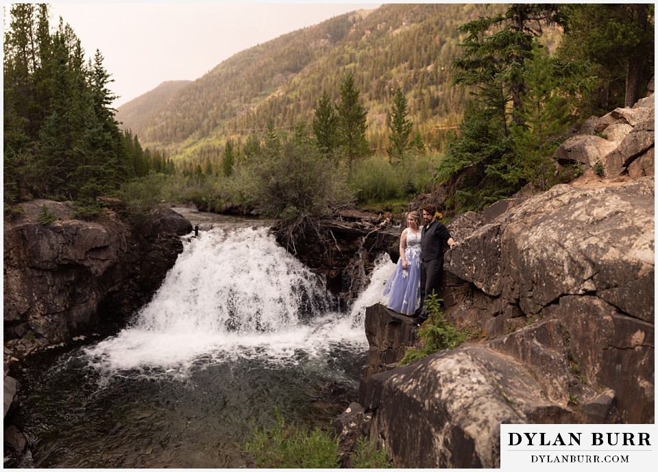 mountain adventure elopement wedding colorado newlywed couple looking out over the river and waterfall