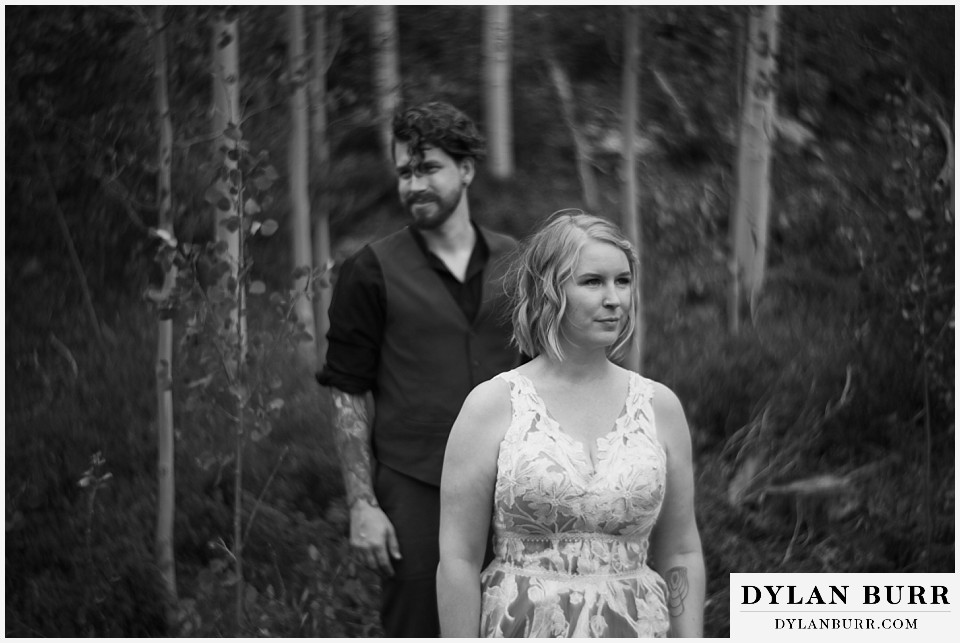 mountain adventure elopement wedding colorado bride and groom walking out from forest black and white photograph