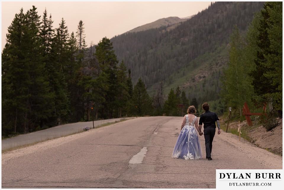 mountain adventure elopement wedding colorado bride and groom walking off together on mountain road into the sunset