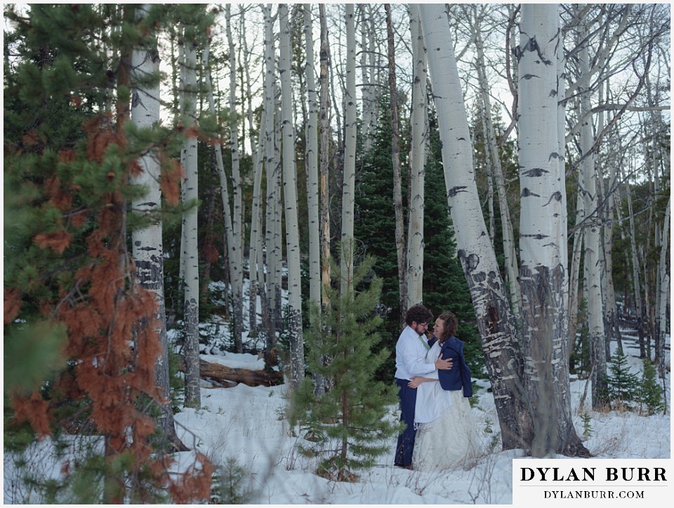 November elopement wedding in rocky mountain national park groom gives jacket to wife in aspen trees