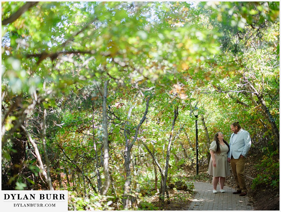 proposal at glen eyrie castle colorado springs walking together on a treelined path