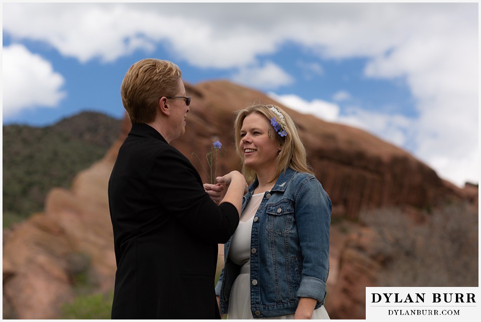 red rocks wedding morrison colorado couple exchaning wildflowers in hair