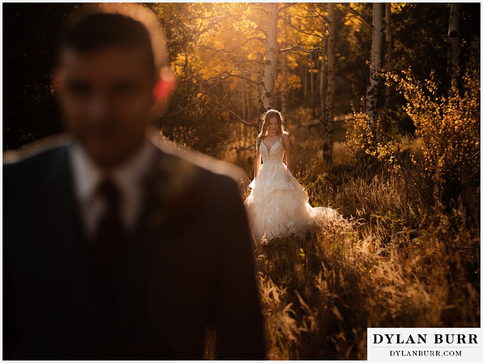 fall ceremony at rhize weddings divide colorado bride in sunset light with groom in the foreground fall aspen trees