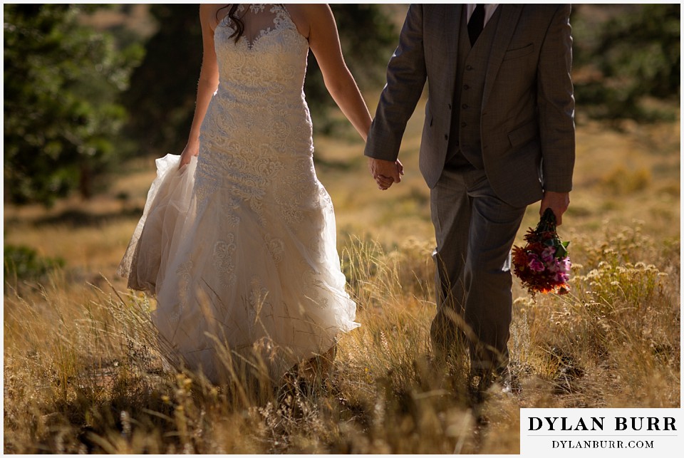 rocky mountain national park elopement wedding bride and groom holding hands in mountain field