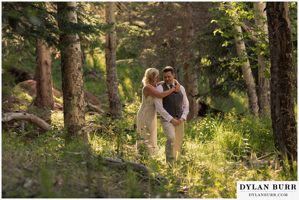 rocky mountain national park wedding elopement bride and groom standing in forest with sunlit glow
