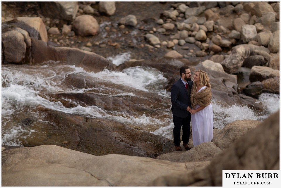 rocky mountain national park wedding elopement bride and groom laughing together in mountains near waterfall