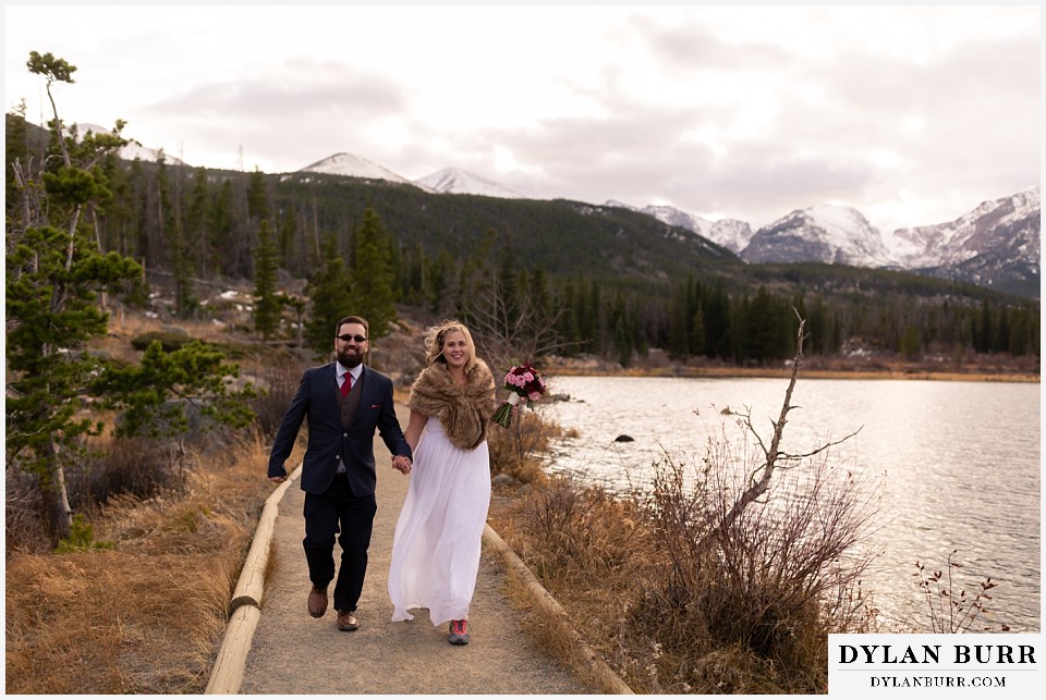 rocky mountain national park wedding elopement bride adn groom running together along lake