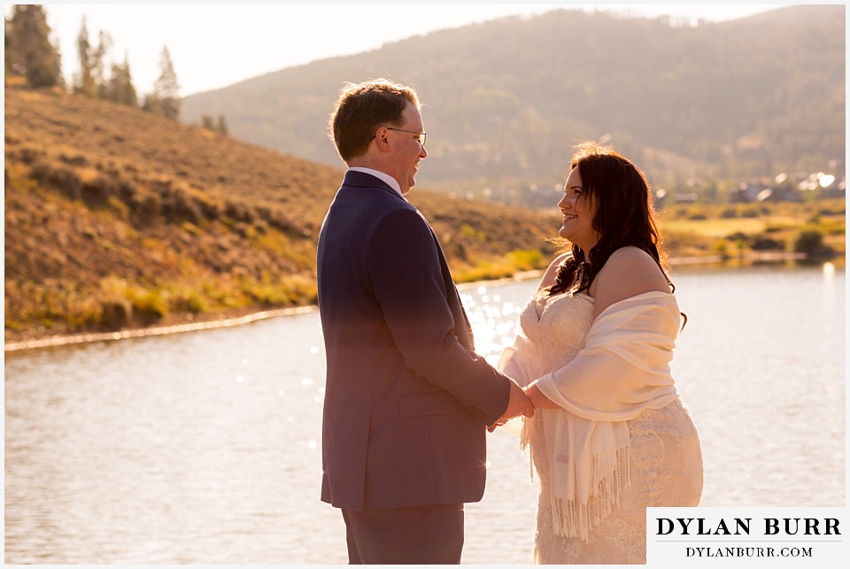 bride and groom standing near lake