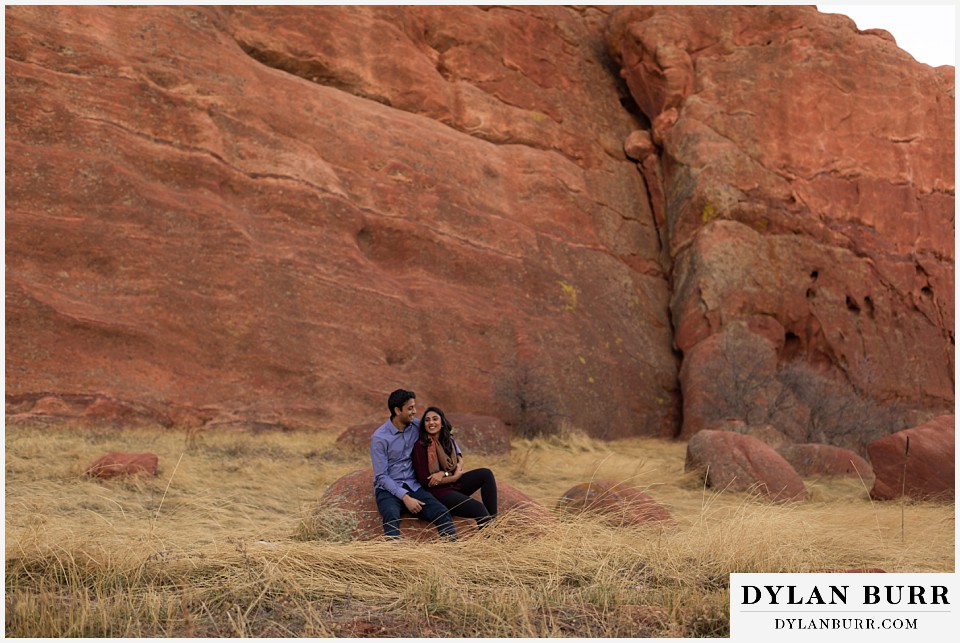 roxborough state park engagement photo session couple sitting on rock with a huge rock wall behind them
