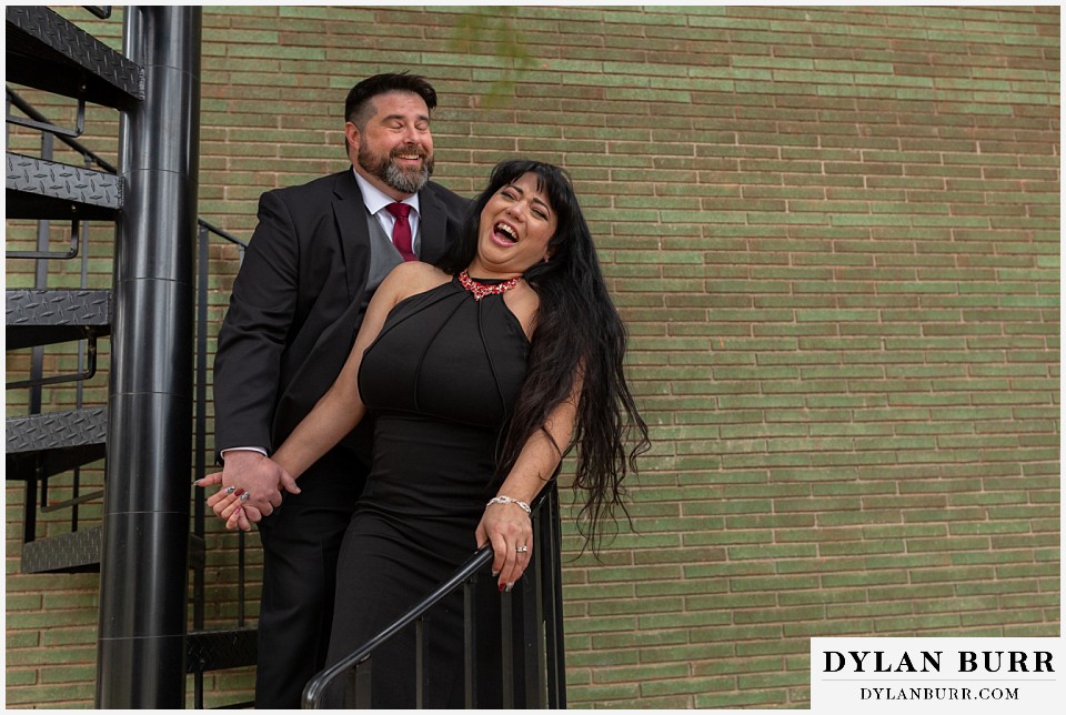 snowmass colorado wedding elopement bride and groom laughing together on spiral staircase with green brick building in background