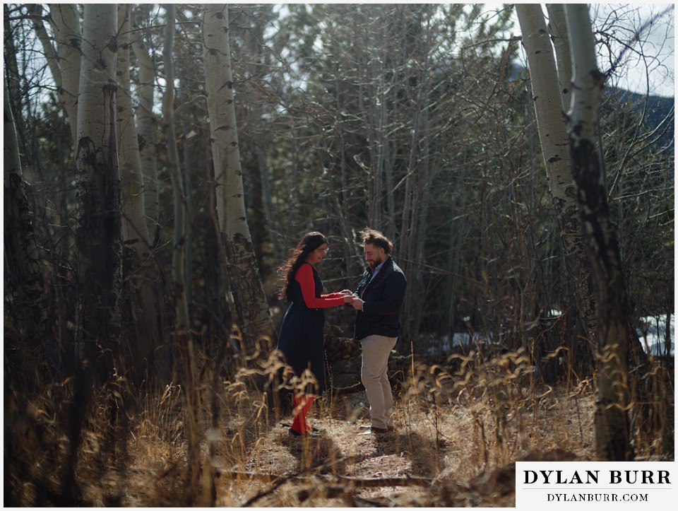 engaged couple standing together in the aspens