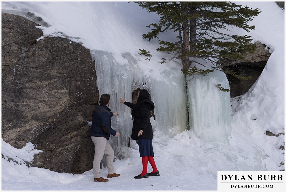 engaged couple checking out massive frozen ice in mountains