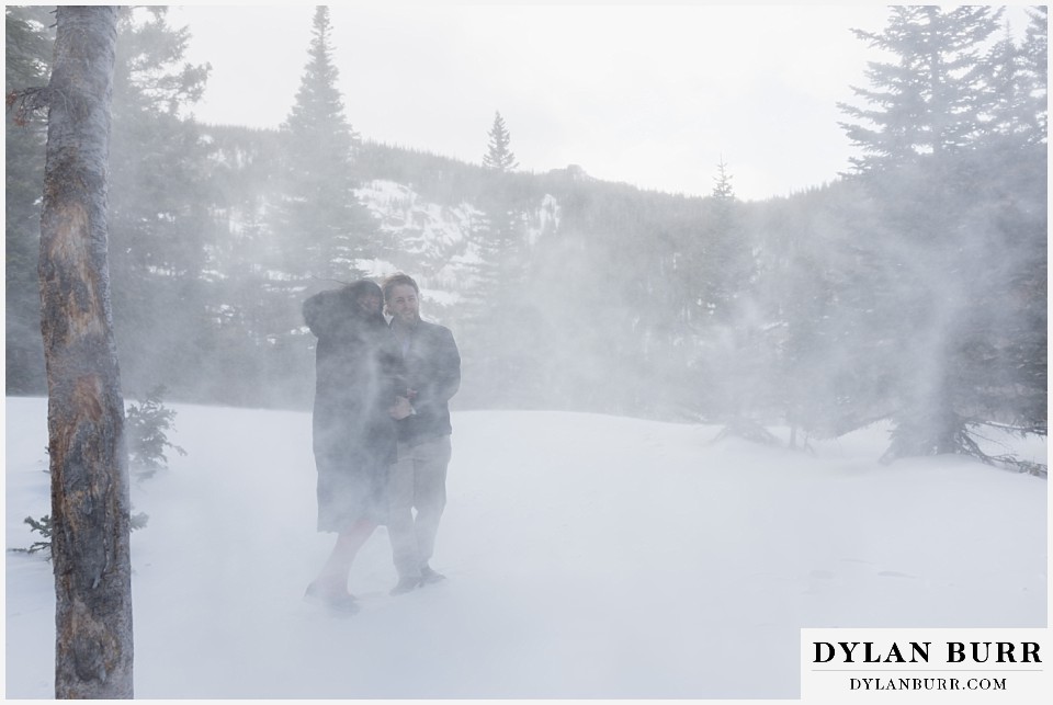 couple in mountains getting blasted with blowing snow and wind