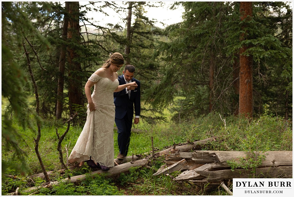 telluride colorado elopement wedding adventure bride and groom crossing some fallen pine trees