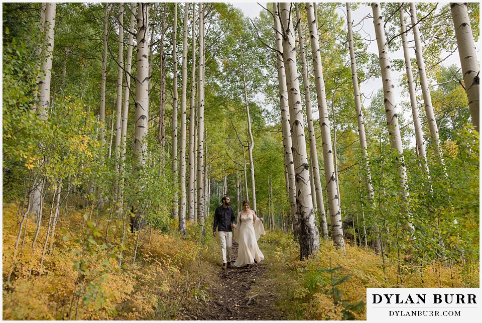 telluride trout lake elopement wedding couple walking down forest path in aspen trees