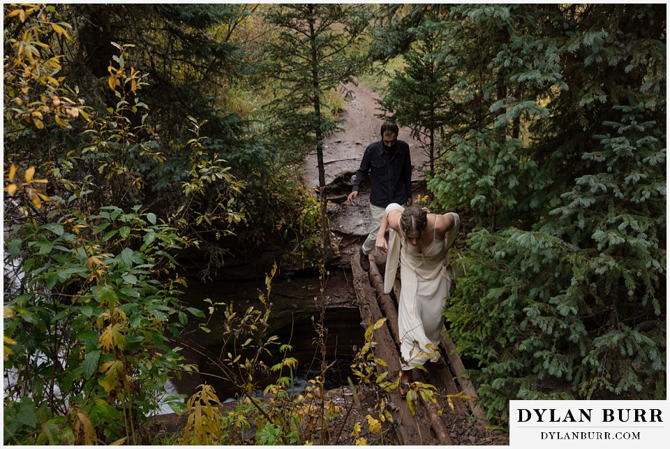 telluride elopement wedding couple crossing creek on handmade bridge