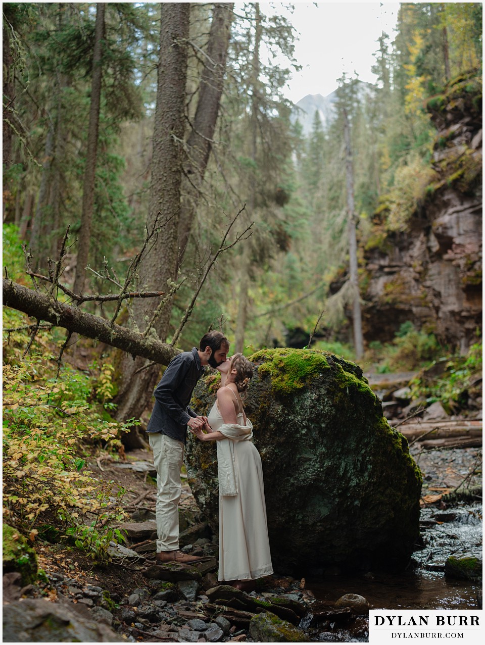 telluride elopement wedding bride and groom kissing riverside by a mossy rock