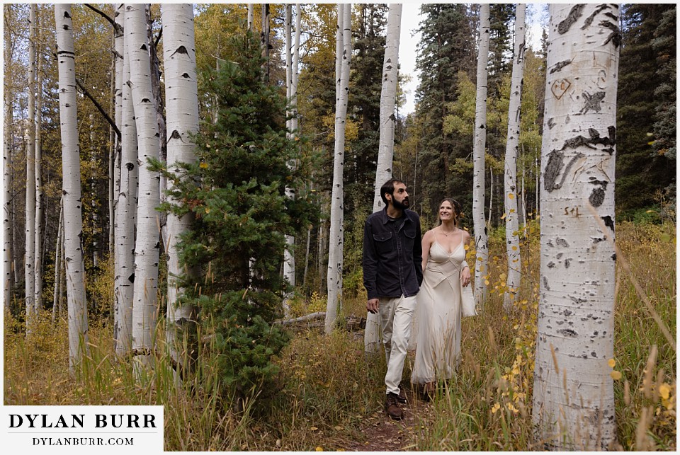 telluride elopement wedding walking together in giant yellow aspen trees