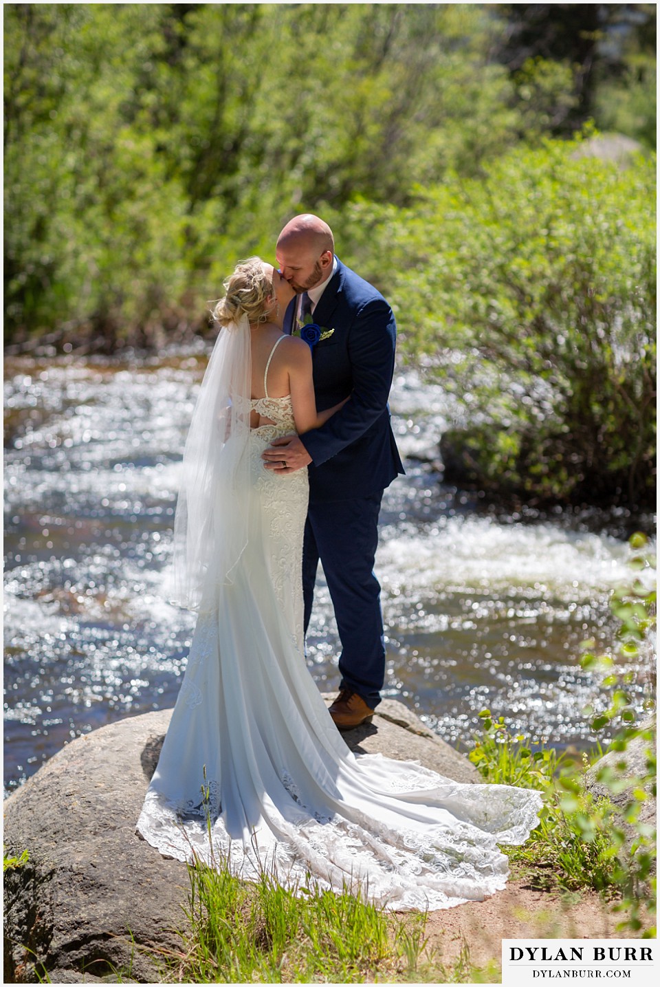 wedding couple kissing alongside the river at wild basin lodge