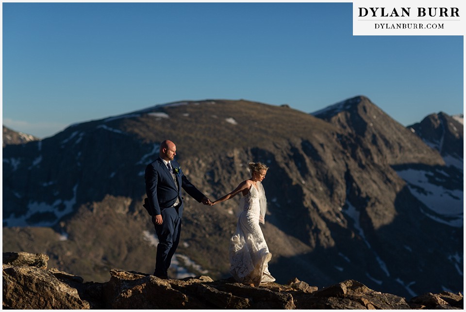bride and groom walking on mountain ridge