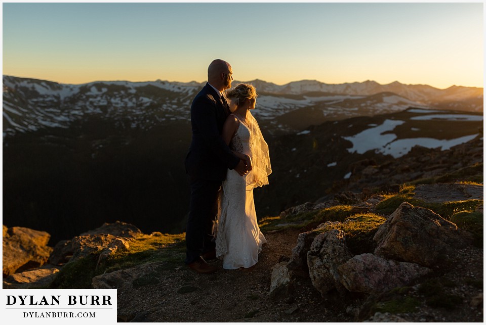 bride and groom watching sunset on mountain top