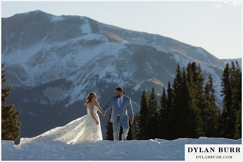 winter elopement wedding near winter park colorado walking along mountain ridge in sunlight