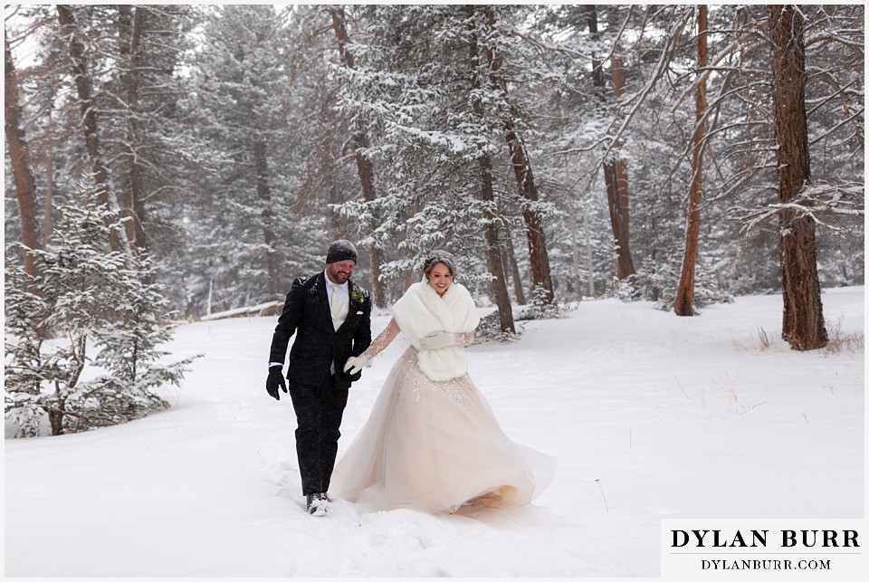 winter wedding newlyweds playing in the snow together in the mountains